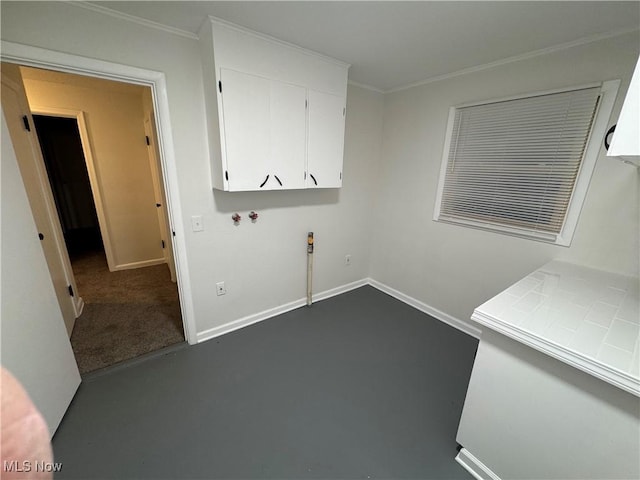 clothes washing area with cabinets and crown molding