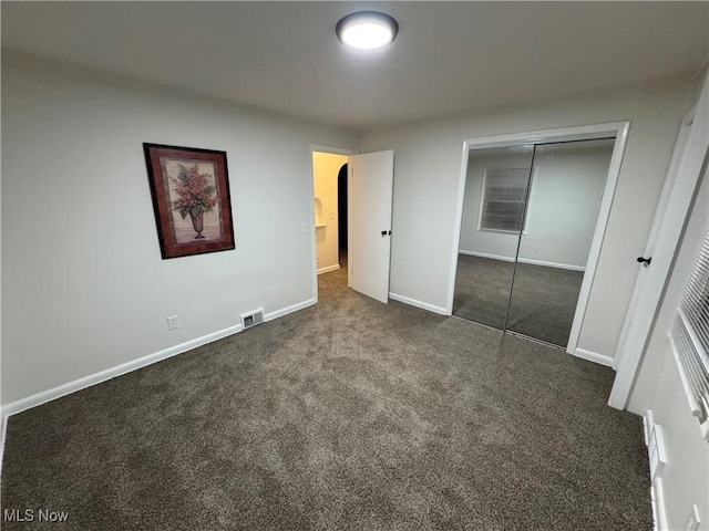 unfurnished bedroom with a closet and dark colored carpet