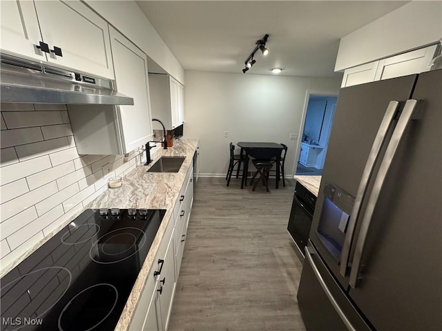 kitchen with stainless steel fridge, black electric stovetop, light stone countertops, white cabinets, and dark hardwood / wood-style flooring