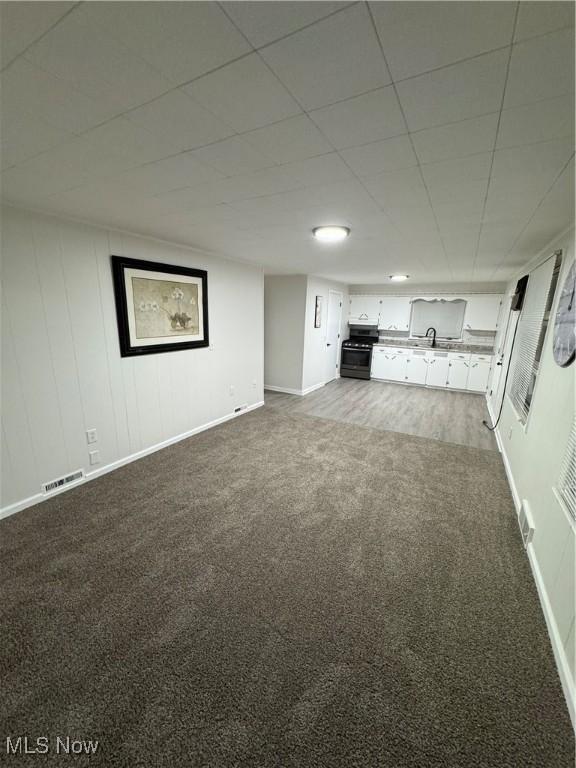 unfurnished living room featuring carpet and sink