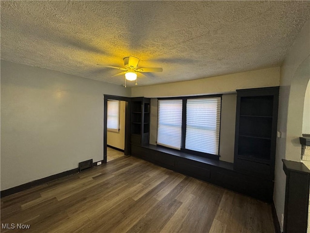 unfurnished room featuring ceiling fan, dark hardwood / wood-style floors, and a textured ceiling