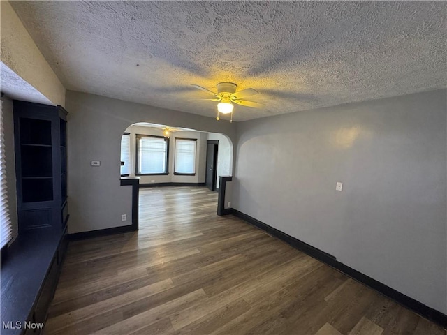 spare room with dark wood-type flooring, ceiling fan, and a textured ceiling