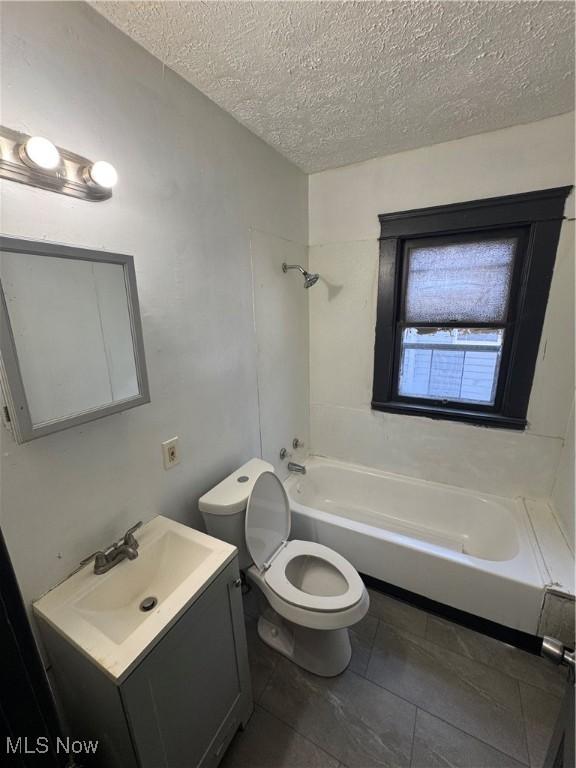 full bathroom featuring vanity, tub / shower combination, toilet, and a textured ceiling