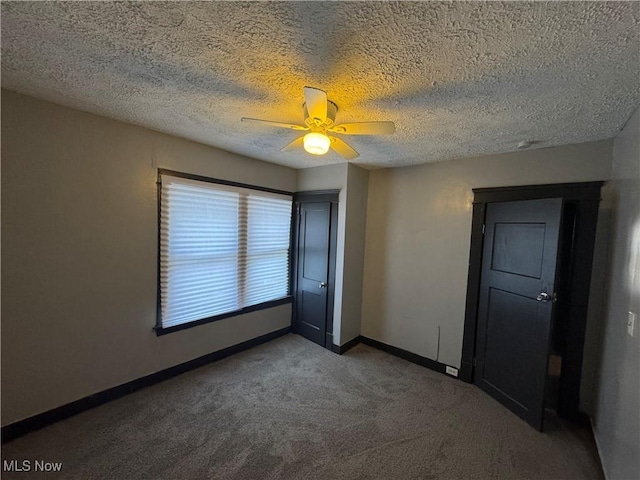 empty room with ceiling fan, a textured ceiling, and carpet