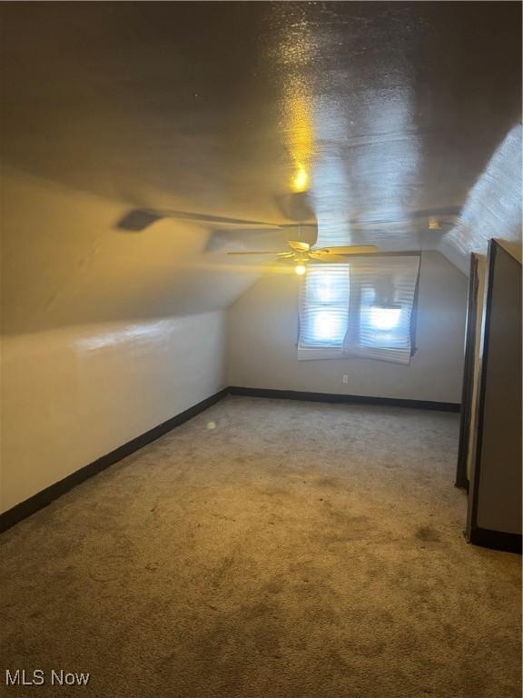 additional living space featuring carpet flooring and vaulted ceiling