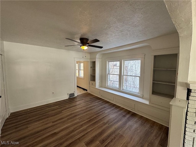 unfurnished living room featuring ceiling fan, dark hardwood / wood-style floors, and a textured ceiling