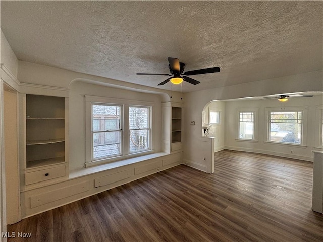 unfurnished living room with dark wood-type flooring, a textured ceiling, and ceiling fan