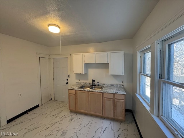 kitchen featuring white cabinetry, sink, a textured ceiling, and a healthy amount of sunlight