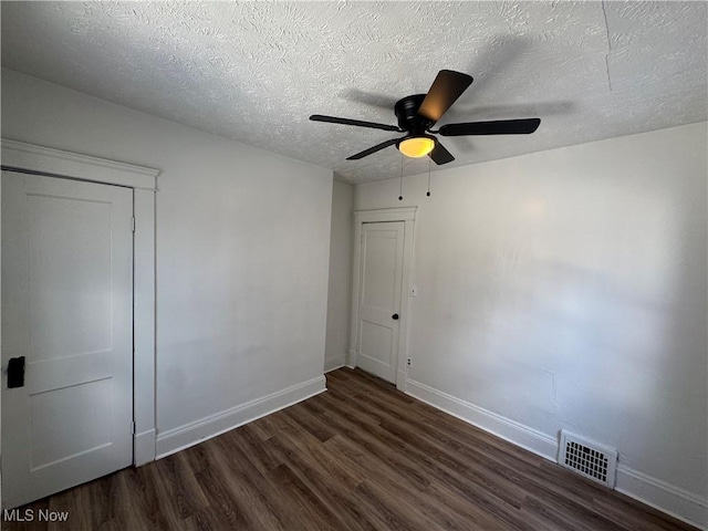 unfurnished bedroom featuring dark hardwood / wood-style flooring, a textured ceiling, and ceiling fan