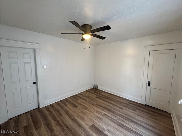 empty room with ceiling fan, dark hardwood / wood-style flooring, and a textured ceiling