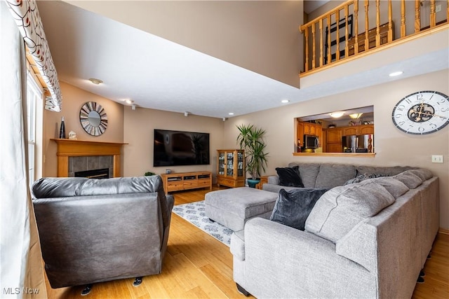 living room featuring a fireplace, light hardwood / wood-style flooring, and a high ceiling