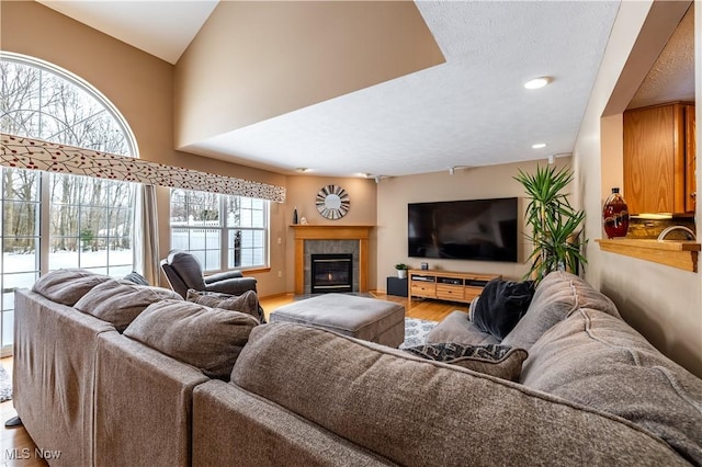 living area with a textured ceiling, wood finished floors, and a tiled fireplace