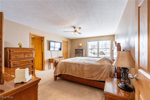 bedroom featuring ceiling fan, light colored carpet, and a textured ceiling