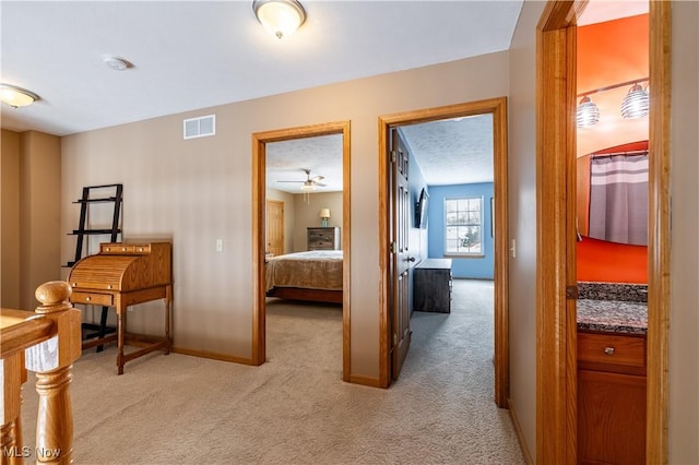 corridor with light colored carpet and a textured ceiling