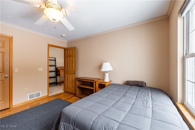 bedroom featuring multiple windows, crown molding, ceiling fan, and light wood-type flooring