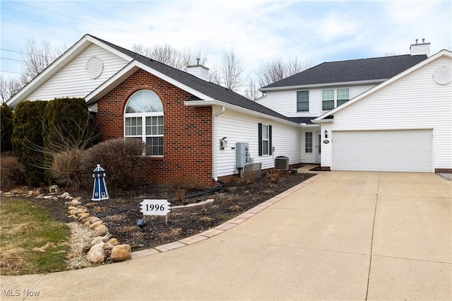 traditional-style home featuring cooling unit, brick siding, driveway, and a chimney