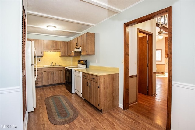 kitchen with sink, white appliances, tasteful backsplash, and wood-type flooring