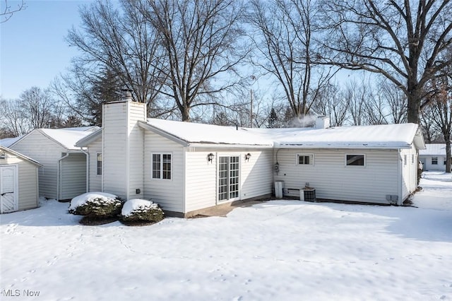 snow covered rear of property featuring central air condition unit