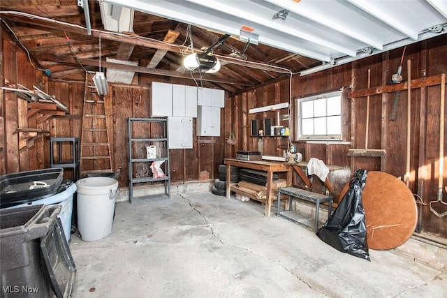 garage featuring a workshop area, a garage door opener, and wooden walls