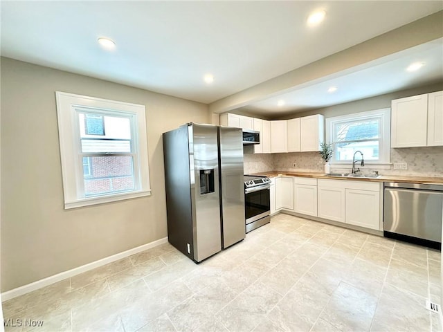 kitchen featuring decorative backsplash, sink, white cabinets, and stainless steel appliances