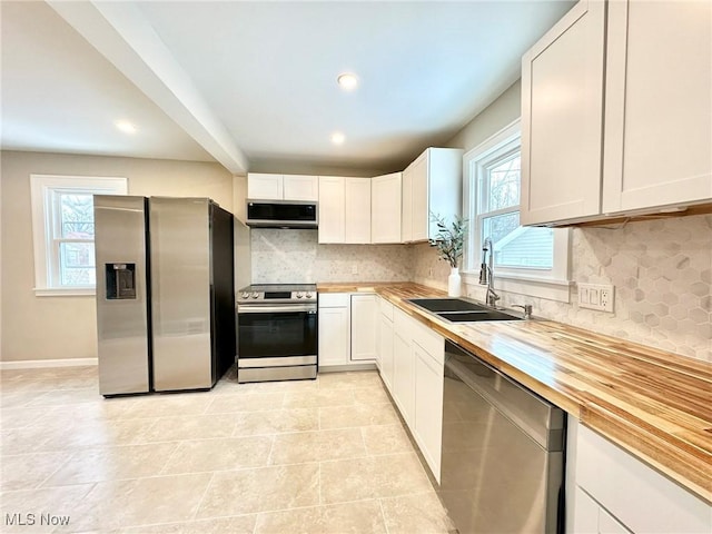 kitchen with white cabinets, stainless steel appliances, and butcher block countertops