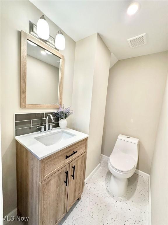 bathroom with vanity, toilet, and decorative backsplash