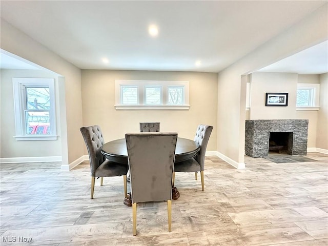 dining room featuring light hardwood / wood-style floors and a stone fireplace