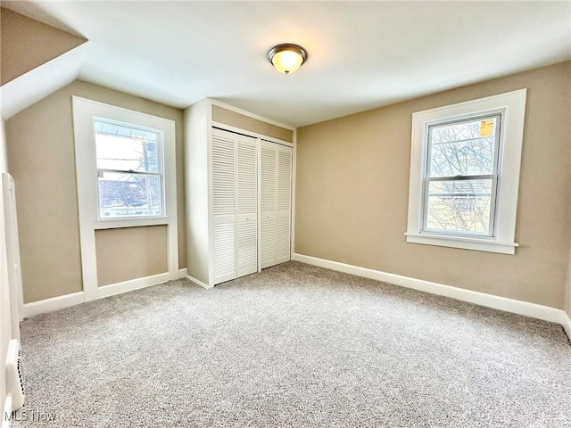 unfurnished bedroom with carpet floors, multiple windows, a closet, and lofted ceiling