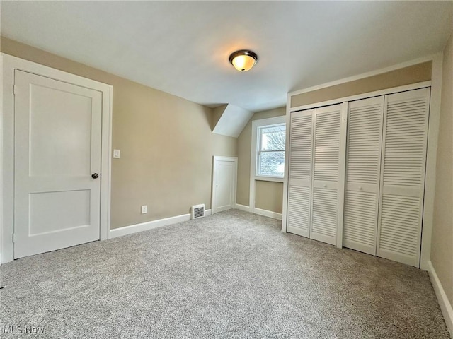 unfurnished bedroom with a closet, vaulted ceiling, and carpet