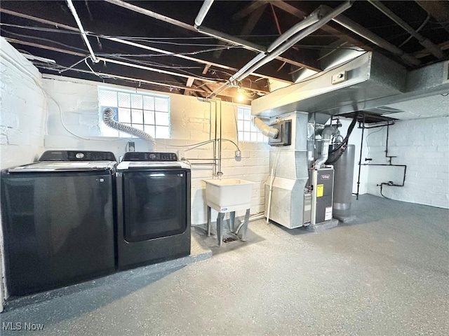 laundry room featuring water heater, sink, heating unit, and independent washer and dryer