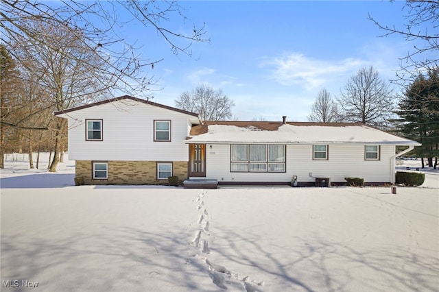 snow covered back of property featuring central AC unit