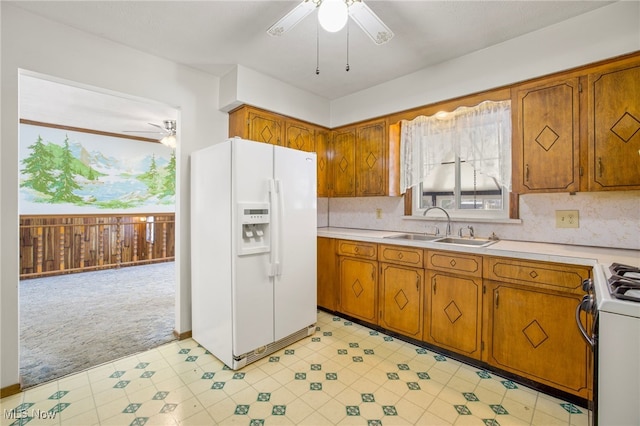 kitchen with ceiling fan, sink, light colored carpet, white appliances, and wood walls