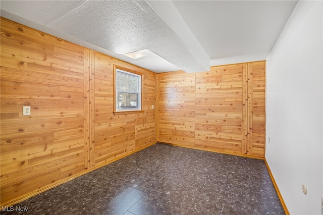 unfurnished room featuring wood walls and a textured ceiling