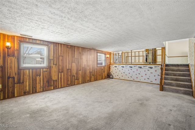 basement featuring wooden walls, a textured ceiling, and carpet