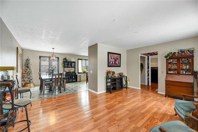 living room featuring an inviting chandelier, light hardwood / wood-style flooring, and a textured ceiling