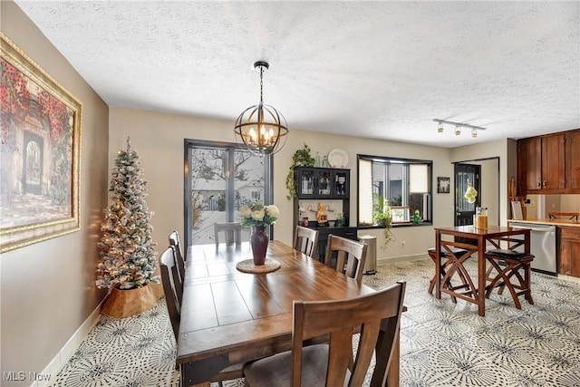 dining space featuring track lighting, a chandelier, and a textured ceiling