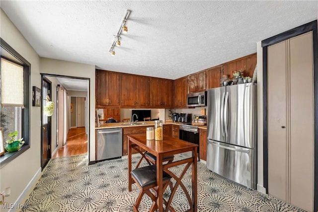 kitchen with sink, rail lighting, a textured ceiling, and appliances with stainless steel finishes