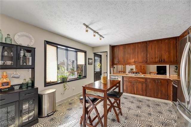 kitchen featuring track lighting, stainless steel appliances, a textured ceiling, and light tile patterned flooring