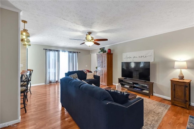 living room featuring crown molding, ceiling fan, hardwood / wood-style flooring, and a textured ceiling