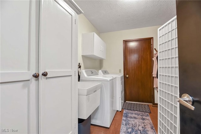 laundry area featuring sink, cabinets, independent washer and dryer, a textured ceiling, and light hardwood / wood-style flooring