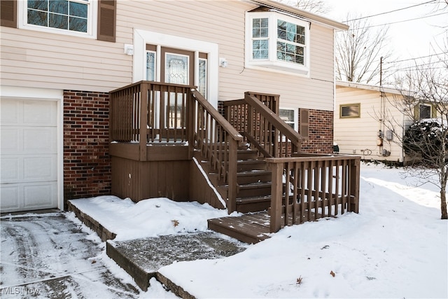 snow covered property entrance featuring a garage