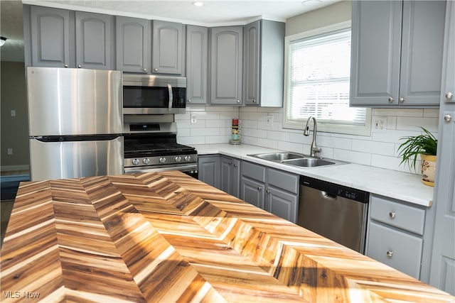 kitchen featuring gray cabinetry, sink, decorative backsplash, and appliances with stainless steel finishes