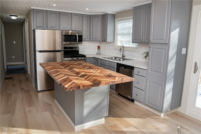 kitchen featuring sink, backsplash, stainless steel appliances, light hardwood / wood-style floors, and a kitchen island