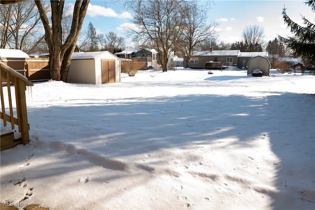 snowy yard featuring a shed