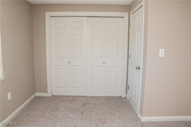 unfurnished bedroom with light colored carpet and a closet