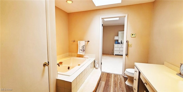 bathroom featuring a relaxing tiled tub, vanity, hardwood / wood-style flooring, and toilet