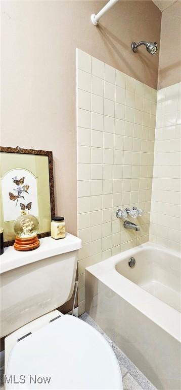 bathroom with tiled shower / bath combo and toilet