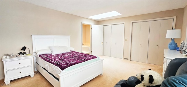 carpeted bedroom with multiple closets and a skylight