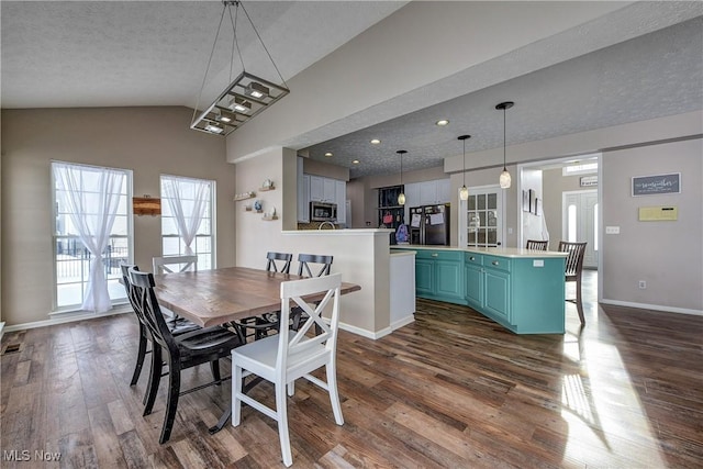 dining room with dark hardwood / wood-style flooring, vaulted ceiling, and a textured ceiling