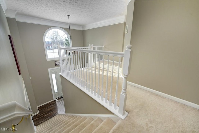 stairs featuring an inviting chandelier, crown molding, a textured ceiling, and carpet